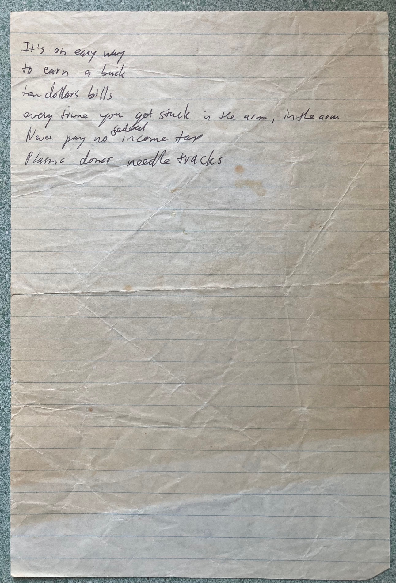 Photo of discolored, slightly wrinkled lined paper with some barely legible writing in black ink.